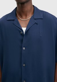 Navyblauw short-sleeve shirt gemaakt van gladde stof, met een kraag, knoopsluiting en een subtiele geborduurde logo op de borst.