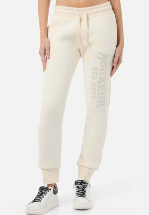 Cremefarbene Jogginghose mit Tunnelzugbund, schmal zulaufenden Bündchen und einem strukturierten Logodetail am linken Bein. Weiches Baumwollmischmaterial.