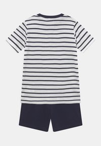 T-shirt en coton rayé avec des bandes horizontales bleu marine et blanches, associé à un short bleu marine. Manches courtes et design à col rond.