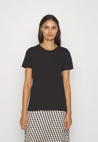 Zwarte katoenen T-shirt met ronde halslijn en korte mouwen, gecombineerd met een patroonrok in geometrische crème- en marineblauwe kleuren.