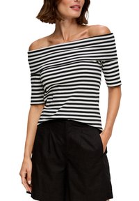 Off-shoulder top met zwart-witte horizontale strepen, met korte mouwen en een relaxed fit, gedragen met donkere shorts.