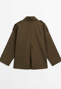 Ruskea trench-coat, jossa on leveä kaulus, kolmen neljänneksen hihat ja olkatoppaukset. Takana on halkio ja vyötäröllä nappisulku.