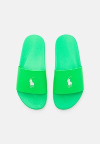 Gröna sandaler gjorda av texturerat gummi, med en bred rem och en vit logotyp. Släta, platta sulor designade för komfort.