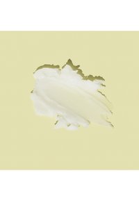 Tache de crème blanche avec des zones lisses et texturées sur un fond beige clair.