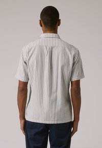 Kortermet skjorte med et lys blått og hvitt vertikalt stripe mønster, klassisk krage og en skreddersydd passform med rett kant.