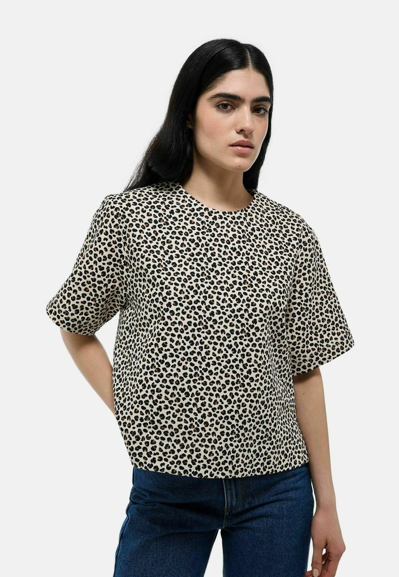 Haut à manches courtes en imprimé léopard beige et noir, avec une coupe décontractée et un col rond, fabriqué en tissu léger.