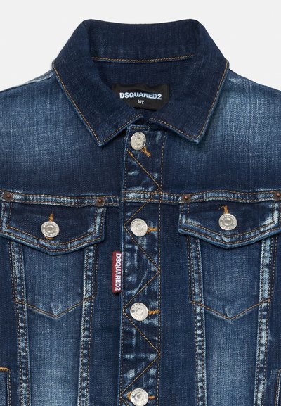 Jeansjacka i mörkblått med metallknappar, kontrasterande sömmar och två bröstfickor. Har en märkeslapp på vänster sida.