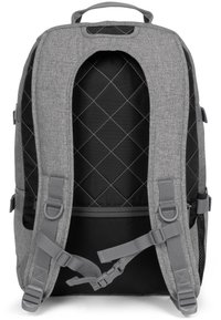 Zaino in tessuto grigio con interno trapuntato nero, spallacci regolabili, maniglia superiore, tasca laterale in rete e chiusure a fibbia frontali.