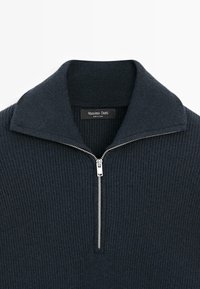 Marineblauer Rippsweater mit einem Reißverschluss-Kragen und silbernem Reißverschlussdetail. Das Etikett trägt die Aufschrift "Massimo Dutti." Weiche Textur, figurbetontes Design.