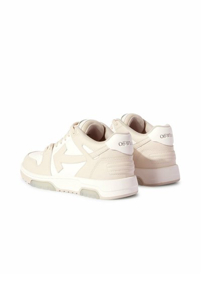 Sneakers in pelle beige con dettagli bianchi, caratterizzate da un colletto imbottito, chiusura con lacci e una suola testurizzata con un distintivo logo a freccia.
