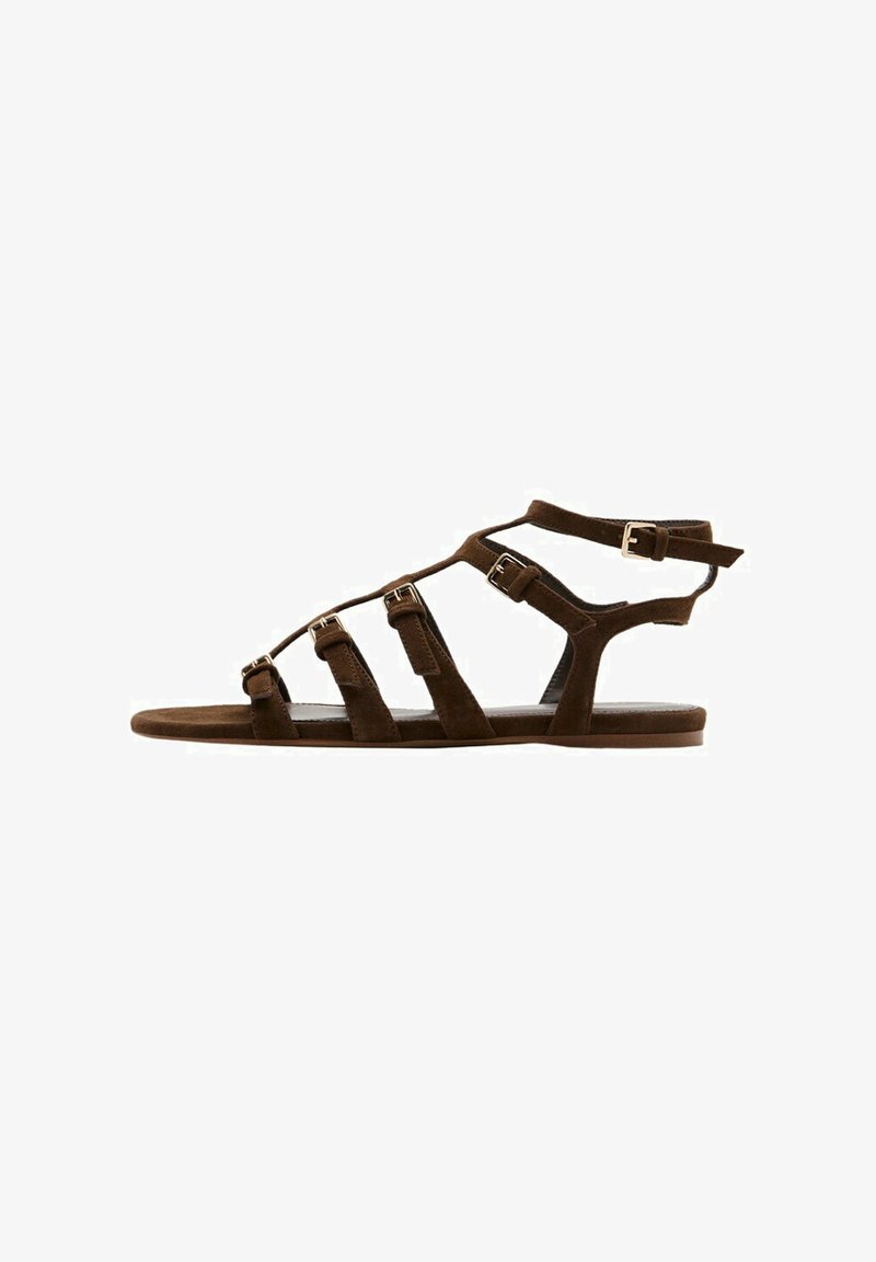 Brun flad gladiatorsandal med flere justerbare spænder og ankellukning vist fra siden.