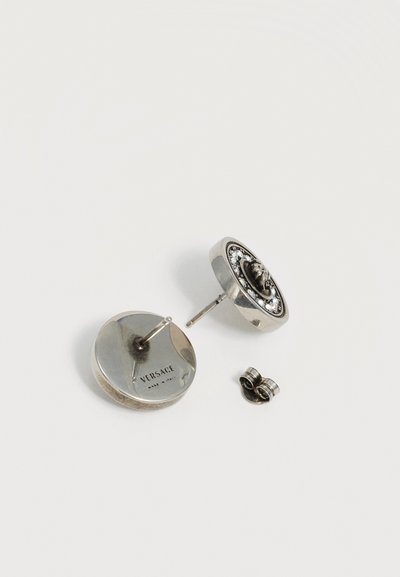 Boucles d'oreilles puces rondes en argent Versace avec tête de Méduse et cristaux, une montrant le dos avec gravure "Made in Italy" et deux attaches d'oreilles.