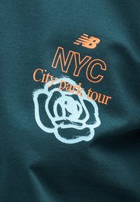 Σκούρο πράσινο ύφασμα με πορτοκαλί κείμενο "NYC City park tour" και πορτοκαλό λογότυπο New Balance πάνω από ένα λευκό αφαίρετο σχέδιο τριαντάφυλλου.