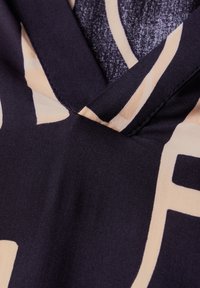 Tessuto di satin con una base blu navy scuro e schemi geometrici in beige chiaro in contrasto. Design a V con una texture liscia e cuciture pulite.