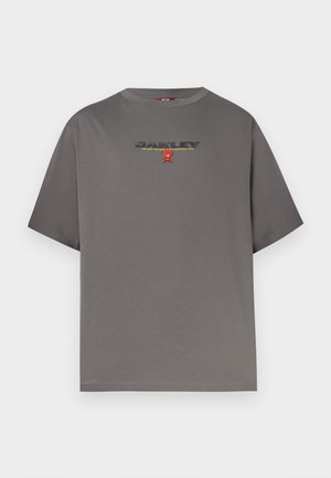 Šedé tričko s krátkým rukávem s nápisem "OAKLEY" a malým červeným motivem uprostřed hrudníku, zobrazené na bílém pozadí.