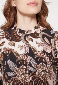 Blusa a maniche lunghe con stampa floreale che presenta una combinazione di colori nera, rosa e verde. Il materiale è liscio, con colletto alla cinese e chiusura a bottoni.