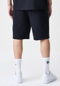 Marineblå bomullsshorts med en avslappet passform som når midt på låret, kombinert med hvite treningssokker og hvite sneakers. Enkelt design, ingen synlige mønstre.