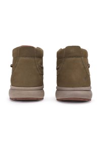 Bruine leren enkelschoenen met een gestructureerde afwerking, grijze rubberen zolen en minimalistische stiksels. Achteraanzicht dat het ontwerp benadrukt.