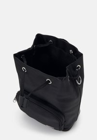 Czarna torba typu bucket z sznureczkiem, wykonana z nylonu, z metalowymi elementami w kolorze srebra, zewnętrzną kieszenią na zamek oraz miękkim, teksturowanym wykończeniem. Otwarte w górnej części.