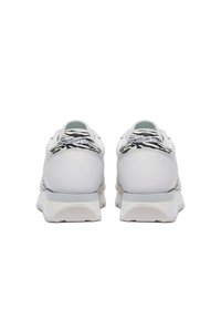 Scarpe da ginnastica bianche con un design accentato in bianco e nero a trama, dotate di suola ammortizzata e lacci piatti per una vestibilità sicura.