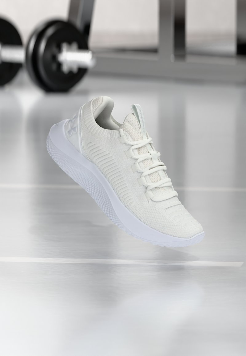 White athletic sneaker with a textured mesh upper and lacing system, featuring a cushioned white sole and subtle ribbed accents.