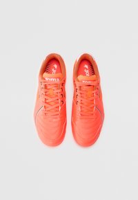 Adidași sport de culoare portocalie strălucitoare, cu un superior sintetic texturat, accente negre contrastante și șireturi plate. Tălpile interne cu amortizare sunt vizibile în interior.