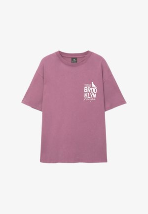 Paarse katoenen t-shirt met korte mouwen, met witte tekst "11202 BROOKLYN New York" en een vogelafbeelding op de linkerkant van de borst.