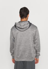 Grauer Hoodie mit einer strukturierten, melierten Oberfläche. Verfügt über eine kontrastierende dunkle Kapuze und elastische Bündchen. Die Rückansicht zeigt einen lockeren Schnitt.
