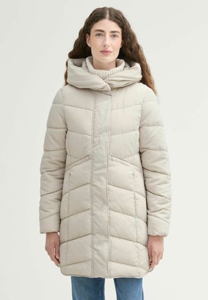 Manteau rembourré beige avec un col haut, présentant un motif matelassé et des poches latérales. Tissu doux et lisse avec une coupe décontractée.