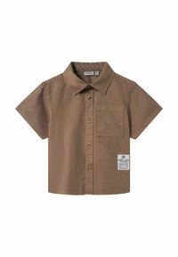 Chemise brune à manches courtes en coton, avec un col, une poche poitrine et une étiquette avec des détails textuels sur le bas.
