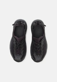 Czarne sportowe buty z teksturowaną siateczką górną i syntetycznymi nakładkami, z sznurowanym zapięciem i odblaskowymi akcentami.