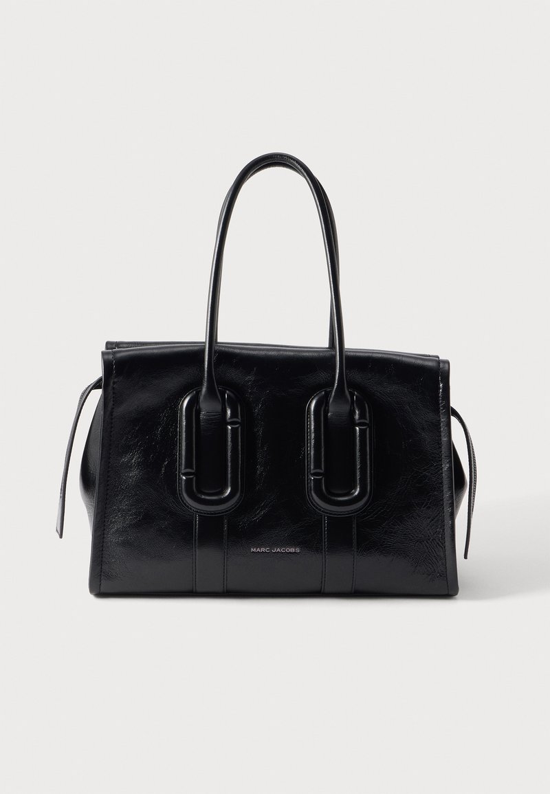 Sac à main en cuir noir Marc Jacobs avec doubles poignées et une forme rectangulaire structurée sur un fond clair.