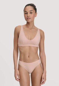 Lichtroze beha en bijpassende slip met kanten afwerking. De beha heeft een V-hals ontwerp en zachte stof, terwijl de slip een gladde afwerking heeft.