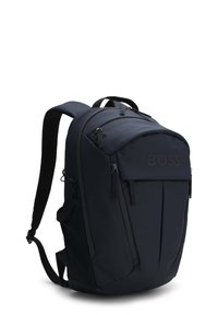 Navy nylon backpack with padded shoulder straps, zippered compartments, and a subtle embossed logo on the front. Textured fabric accents.