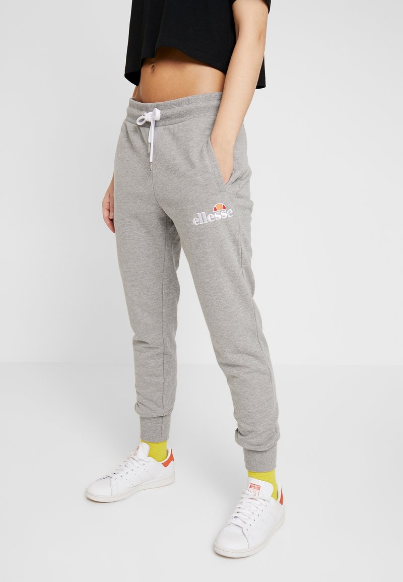 Grå sweatpants med elastisk midjeband och dragsnöre, med sidofickor och en broderad logotyp. Kombinerad med vita sneakers och färgglada strumpor.
