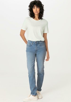 Lichtgroene katoenen t-shirt gecombineerd met hooggepaste blauwe denim jeans. De jeans hebben een rechte snit en een lichte vervaging, aangevuld met witte sneakers.