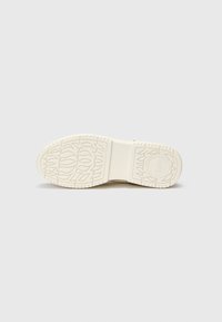 White rubber shoe sole featuring a textured pattern with leaf designs and branding in the center. Flat profile with a solid appearance.