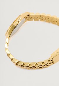 Χρυσόχρονο ρολόι χειρός με στρογγυλή μεταλλική θήκη, αλυσίδα με ημικυκλικούς συνδέσμους και λείο καντράν.