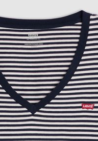 Camiseta a rayas azul marino y blanca con diseño de escote en V, hecha de algodón. Presenta un pequeño parche con el logo rojo de Levi's. Textura suave, estilo casual.