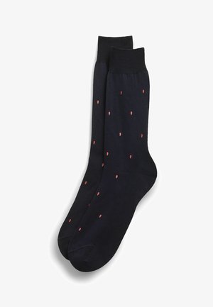 Par sorte crew-sokker med små røde og hvide ispindemønstre jævnt fordelt over stoffet.