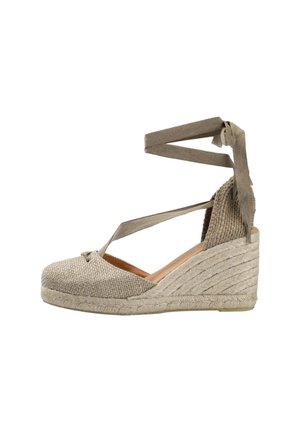Alpargata cuña beige con punta cerrada, suela de yute y cintas de tela que se envuelven alrededor del tobillo para sujetar.