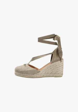 Alpargata cuña beige con punta cerrada, suela de yute y cintas de tela que se envuelven alrededor del tobillo para sujetar.