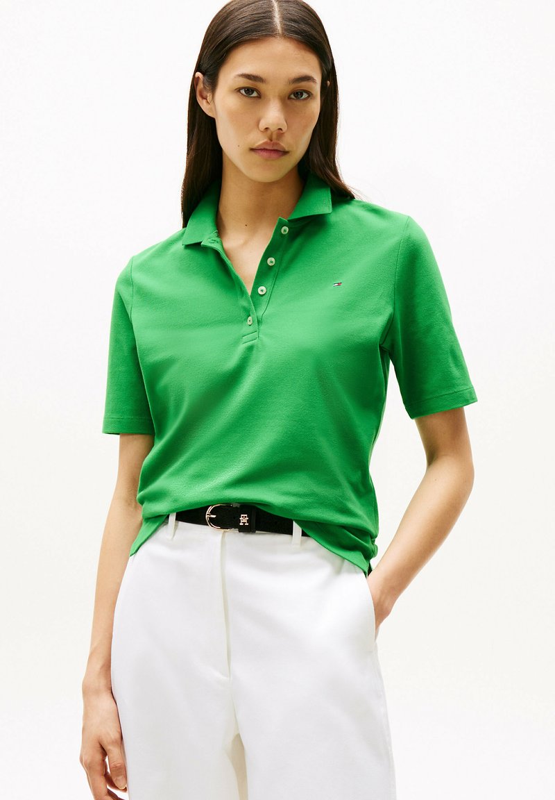 Zielona koszulka polo z kołnierzykiem, krótkimi rękawami i trzema guzikami. Nosić z białymi spodniami i czarnym paskiem z złotą klamrą.