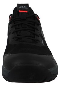 Czarne sportowe buty z siateczkową cholewką, czerwonymi akcentami i grubą gumową podeszwą. Posiada system sznurowania oraz logo Adidas na języku.