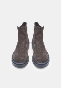 Botine din suede maro, cu vârful rotund, fermoare laterale și o talpă din cauciuc texturat. Prezintă cusături subtile de-a lungul marginilor.