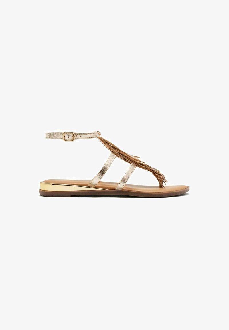 Sandali flat metallici dorati con suola marrone, caratterizzati da tre cinturini e dettagli decorativi in frange. Cinturino alla caviglia regolabile per una vestibilità perfetta.