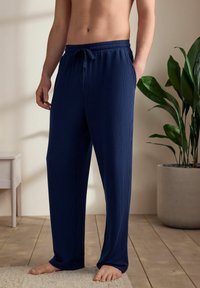 Pantaloni de lounge verticali cu dungi bleumarin, cu talie elastică și cordon; dispune de buzunare laterale și o croială lejeră.