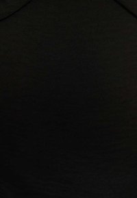 Tissu noir avec une texture lisse, présentant un design simple et minimaliste. Aucun motif ni accent n'est visible dans l'image.