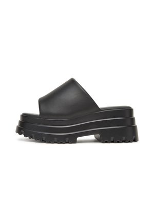 Sandalias negras tipo slide con plataforma, con una correa ancha, textura suave y suela acanalada. Presentan un diseño de suela en capas para mayor altura.