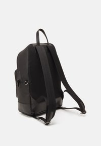 Zaino nero con un design testurizzato in tessuto a rete e dettagli in pelle liscia, spallacci regolabili e una maniglia superiore per il trasporto.